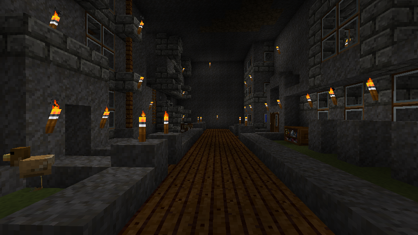 A long corridor with torches and wooden planks on the floor, surrounded by stone walls.