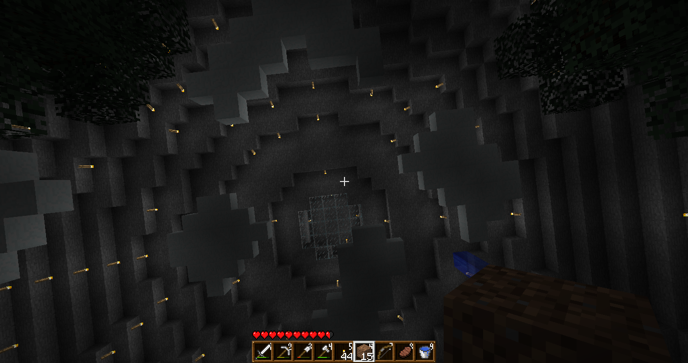 A dark cave with a small pool of water and a few blocks of dirt, surrounded by a large amount of stone and coal ore.