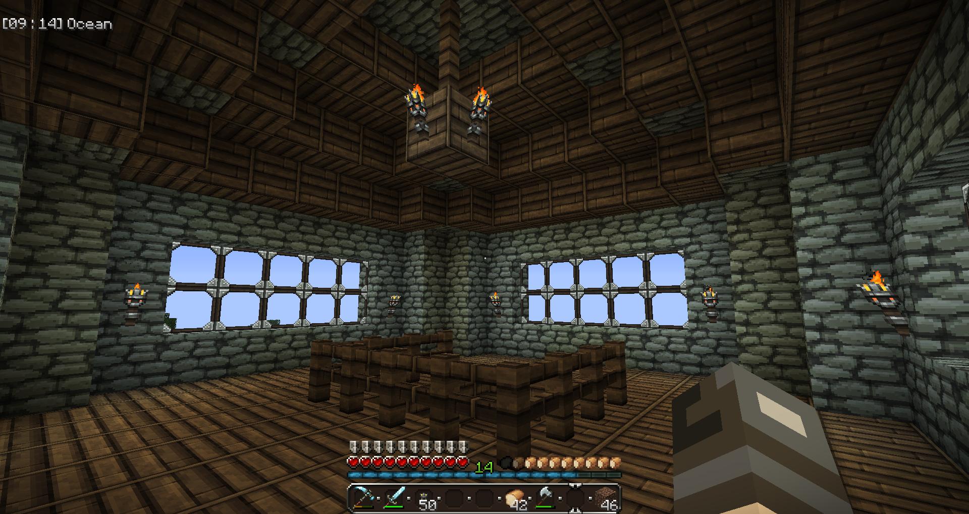 A large stone building with a wooden floor and ceiling, featuring a chandelier and several windows.