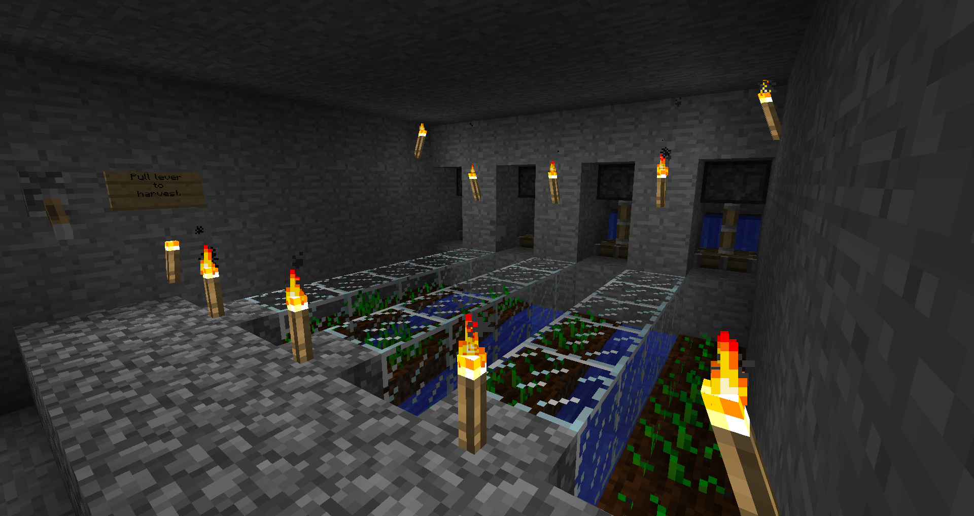 A room with a series of lit torches and a sign on the wall.