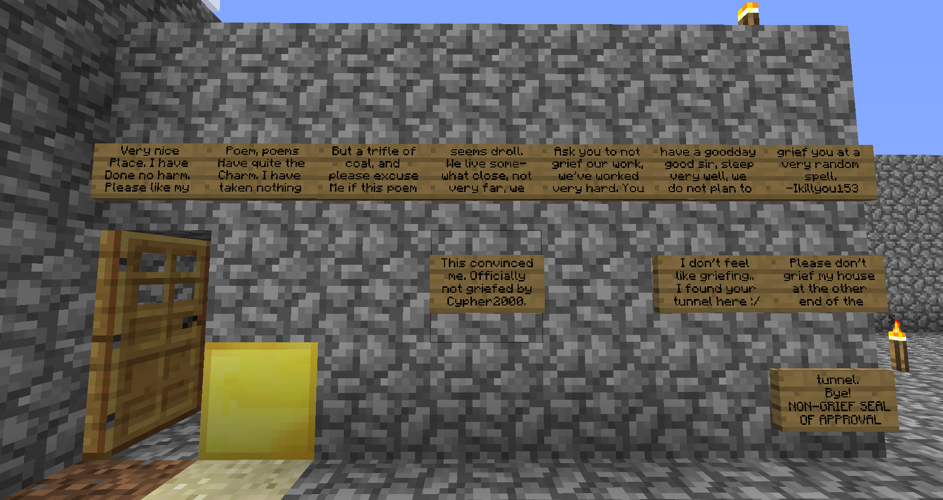 A large stone wall with a wooden door and several signs on it, in a Minecraft world.