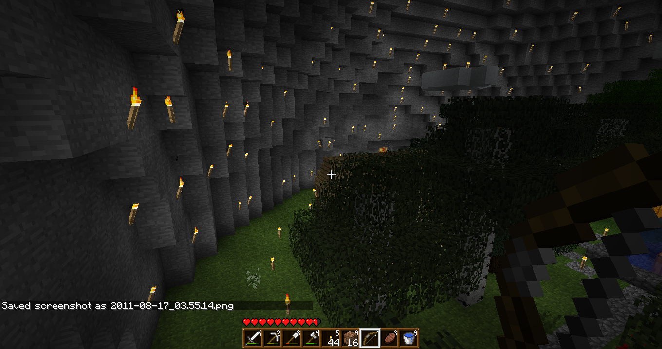 A large underground cave with a grassy floor and a tree in the center, surrounded by a wall of obsidian pillars.
