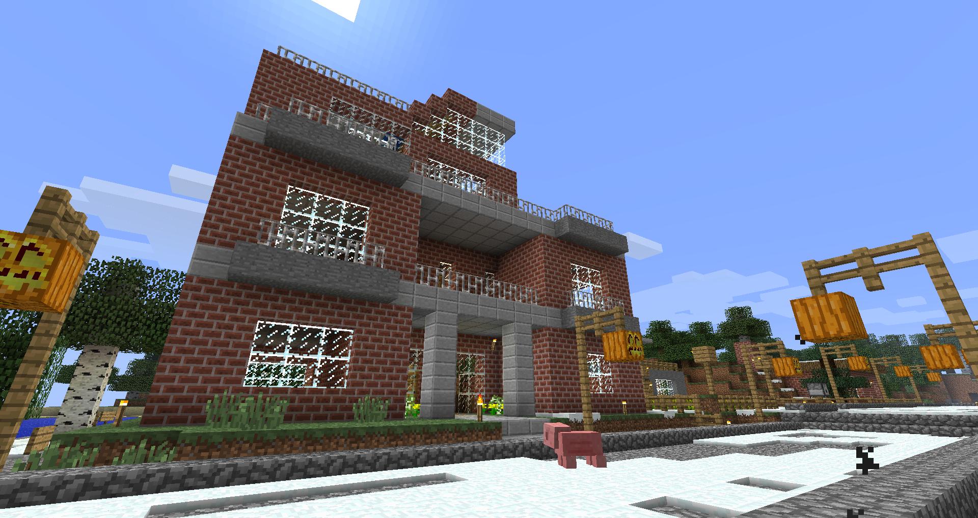 A large brick building with a garden in front of it, surrounded by other buildings and signs.