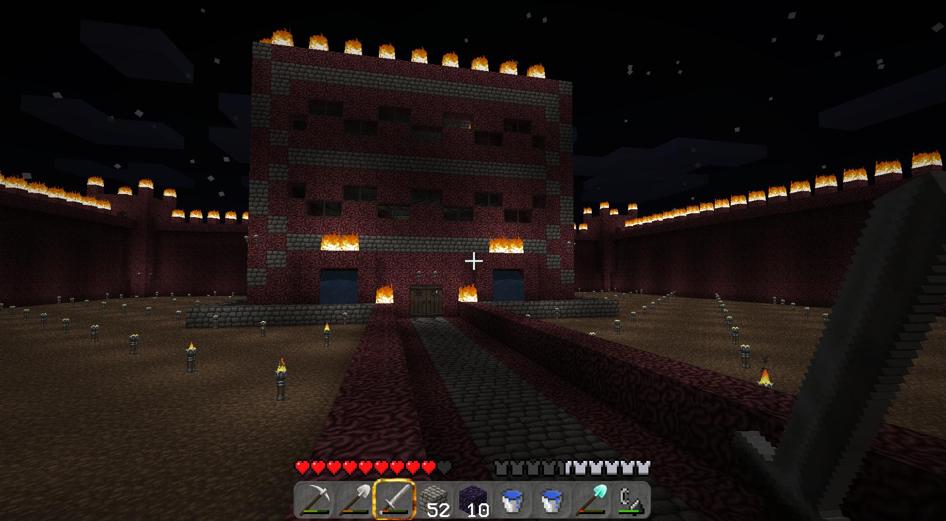 A large red building with a path leading up to it, surrounded by a wall and lit up at night.