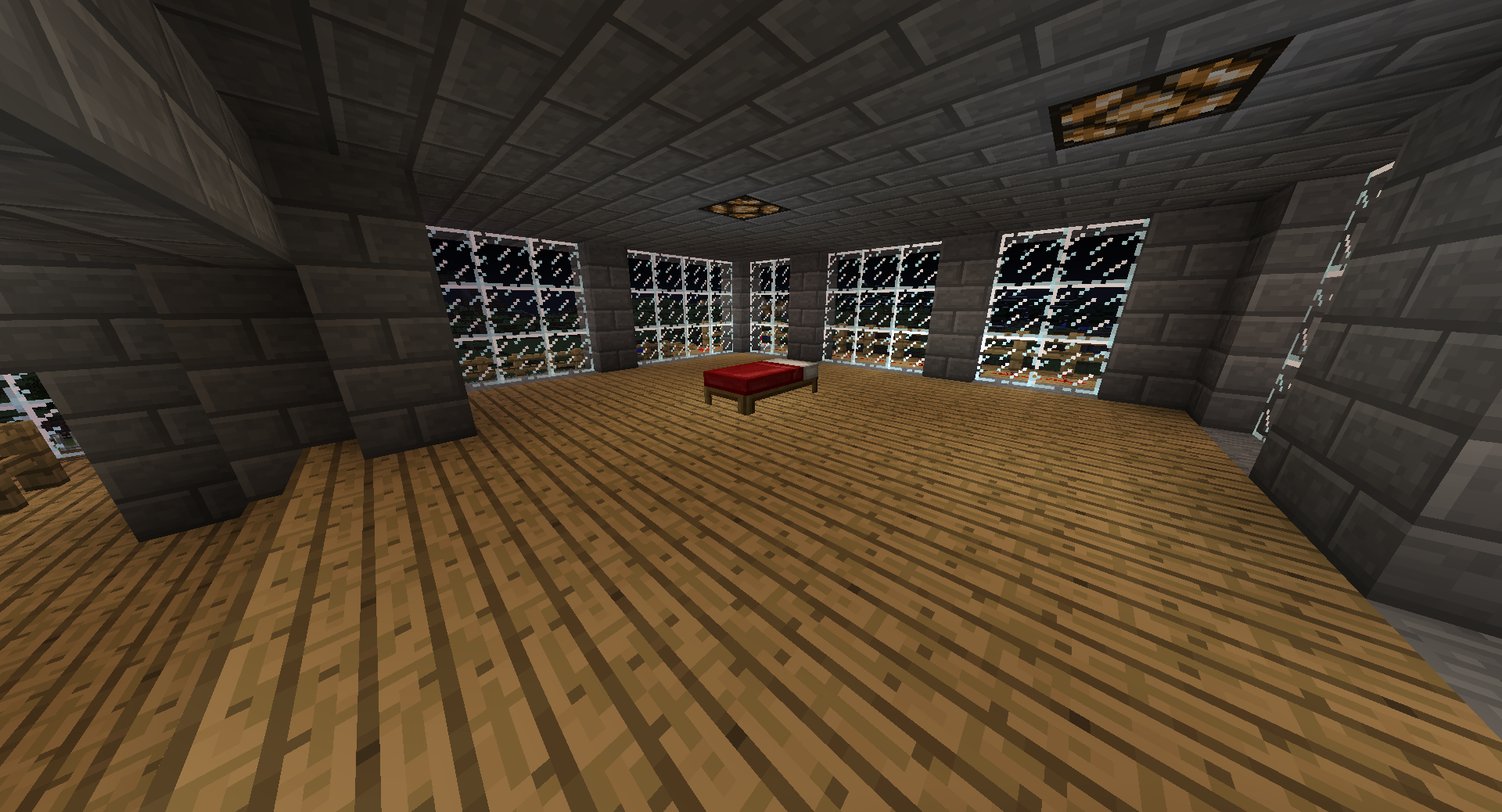 A large room with a wooden floor and stone walls, featuring two red blocks in the center.