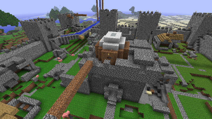 A large castle with a moat and a drawbridge, surrounded by a village.