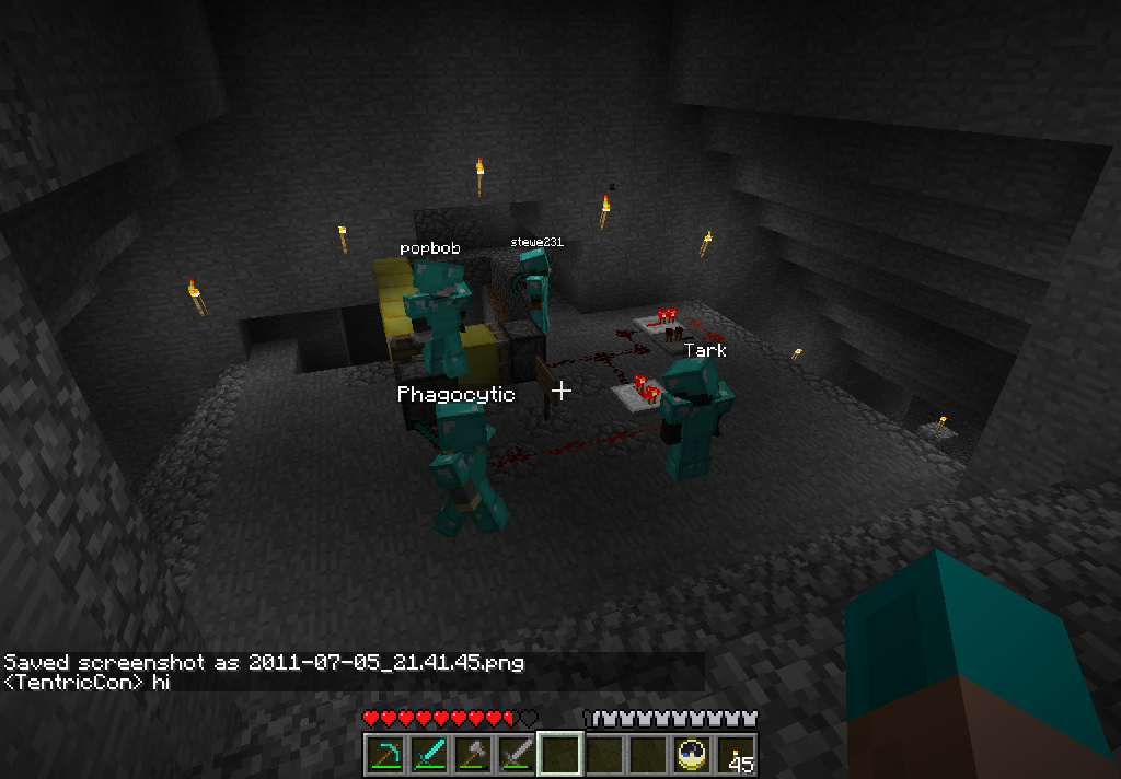 A group of players in a dark cave, with a few signs and chat messages visible.