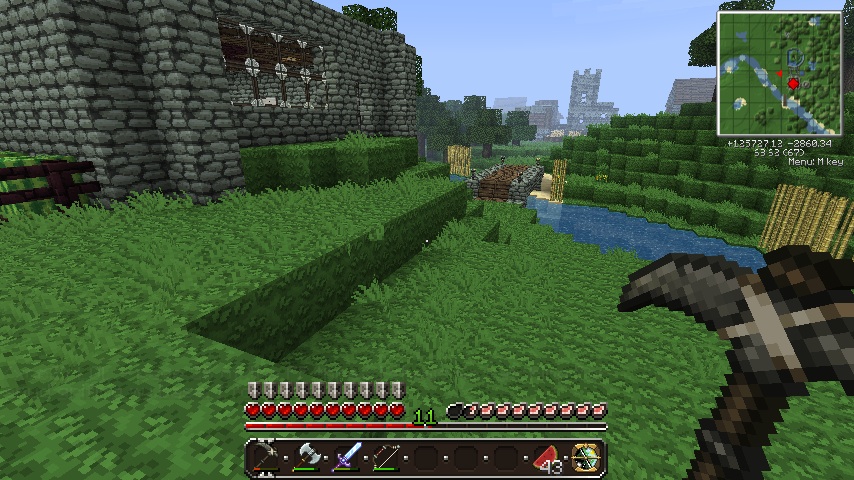 A player is standing in a grassy area with a stone wall and a river nearby. The player's inventory is open, showing various items.