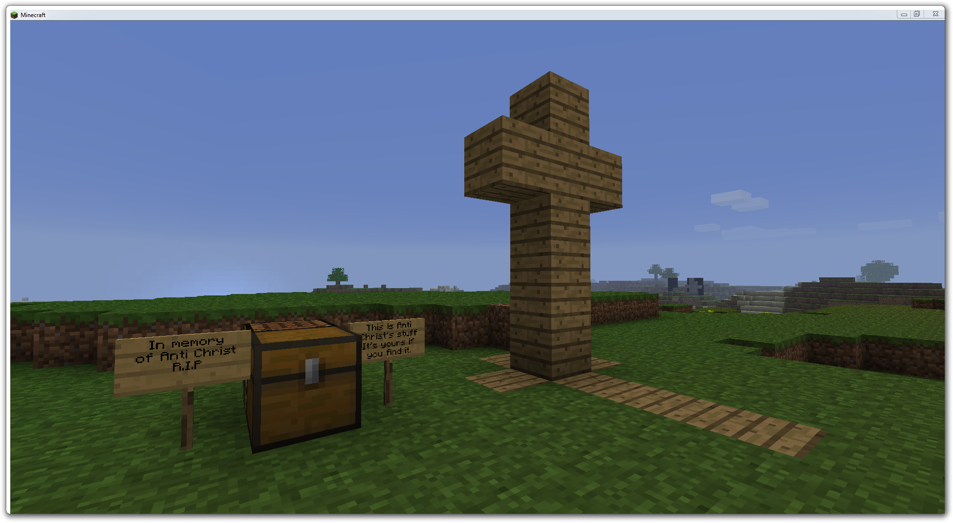 A cross made of dirt blocks, with a chest and signs nearby.