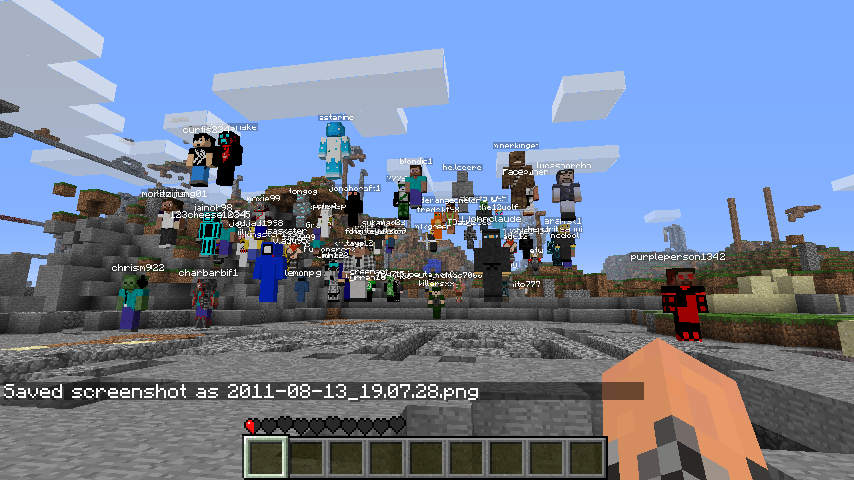 A large group of players gathered in a base, with many signs and chat messages visible.