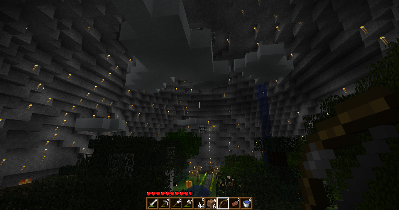 A large, dark cave with a high ceiling and a few trees at the bottom.