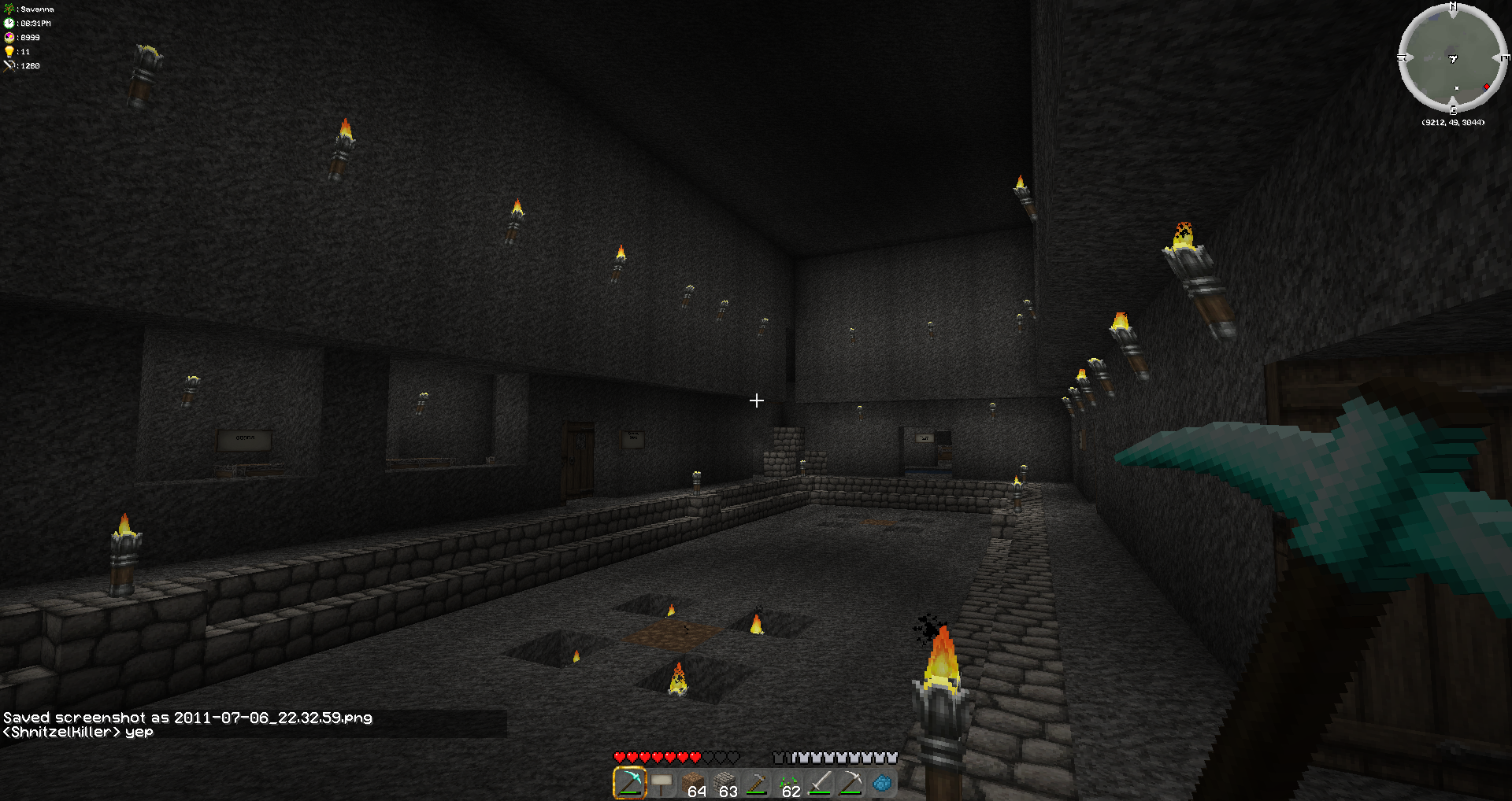 A dark room with a fire in the center and a player standing next to it. The room has a high ceiling and is made of stone blocks.