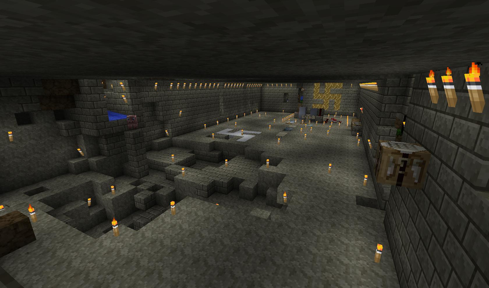 A large underground room with a stone floor and walls, lit by many torches.