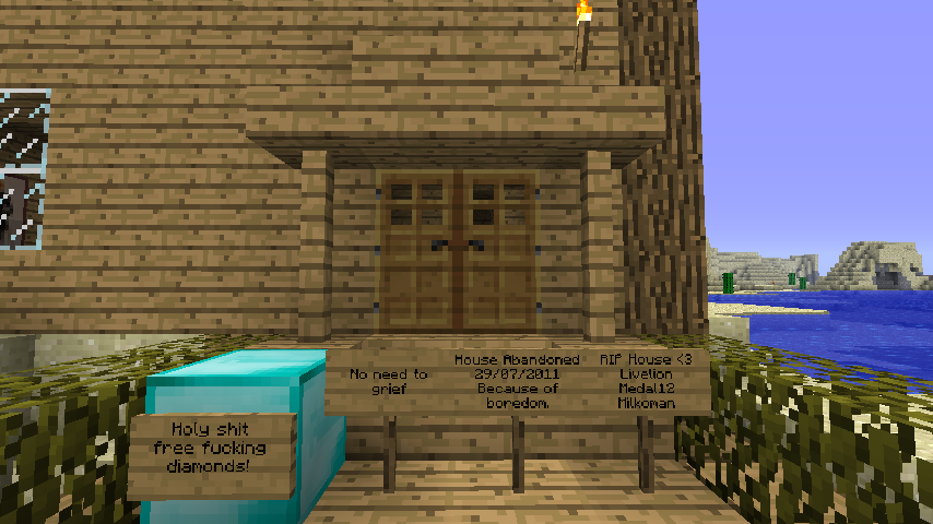 A wooden house with a sign in front of it, and a blue block to the left.