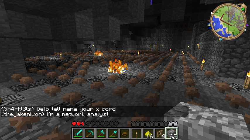 A large underground room with a fire in the center and a map on the wall.